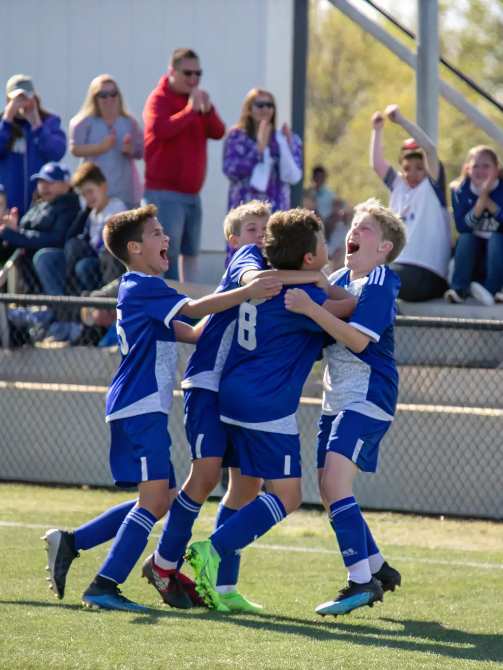 A vibrant photograph capturing a youth soccer team from Union Sportive de Marolles celebrating a goal during a local tournament, showcasing teamwork and sportsmanship.